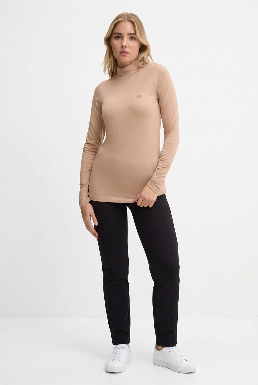 Modella con maglia beige e piccolo logo laterale sul petto