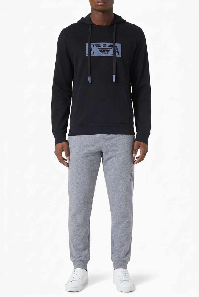 Modello con felpa Emporio Armani scura con logo azzurro e jogger grigi