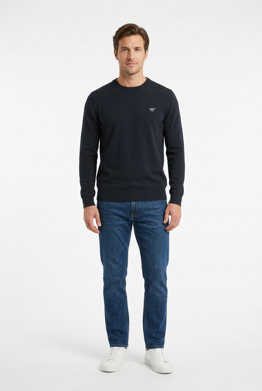 Modello con maglione scuro, jeans indaco e sneakers bianche