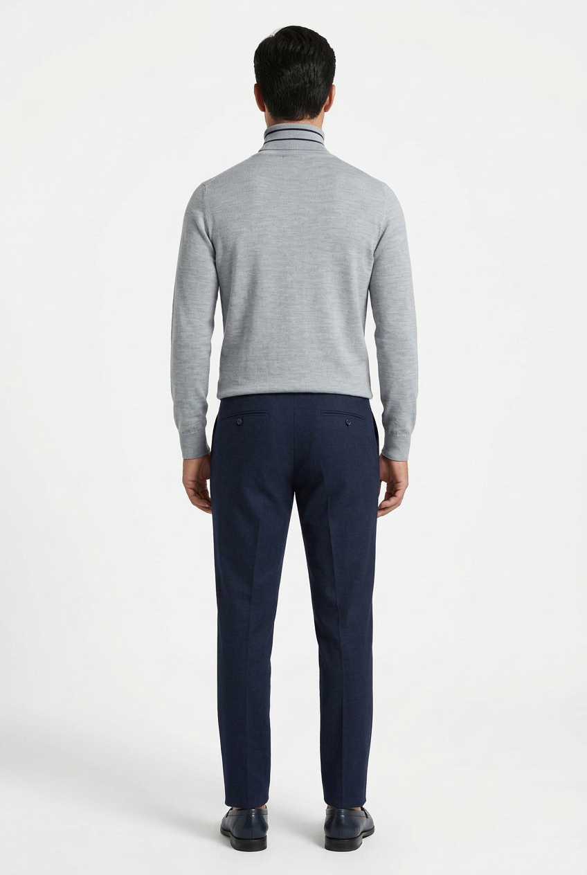 Modello visto da dietro con dolcevita grigio e pantaloni blu a tasche a filo