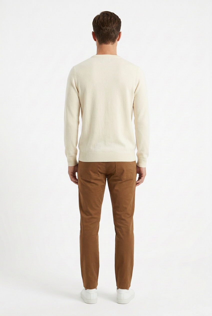 Modello visto da dietro con maglione chiaro, chinos marroni e sneakers bianche